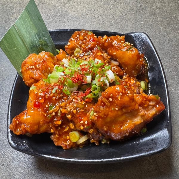 HINODEYA Ramen's fried chicken karaage, coated in a sweet and spicy sauce, garnished with scallions and sesame seeds.