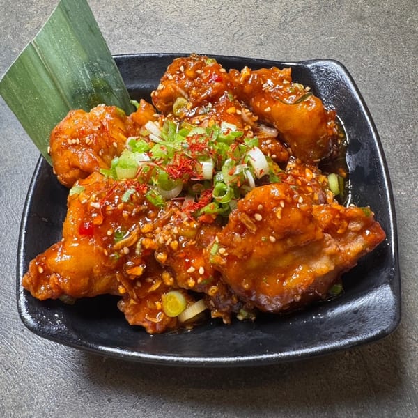 HINODEYA Ramen's fried chicken appetizer, glazed with sauce, sesame seeds, green onions, and chili threads.